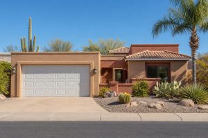 Full exterior view of a Phoenix Arizona home with a closed two-car garage door and desert landscaping, representing garage door opener remote access and curb appeal